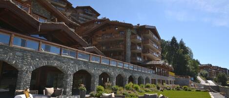 A multi-story hotel with outdoor seating areas and a stone facade.