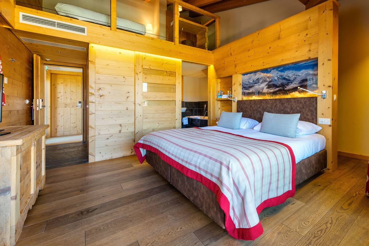 Un dormitorio de cabaña de madera con una cama, un cuadro de montañas y una zona de altillo.