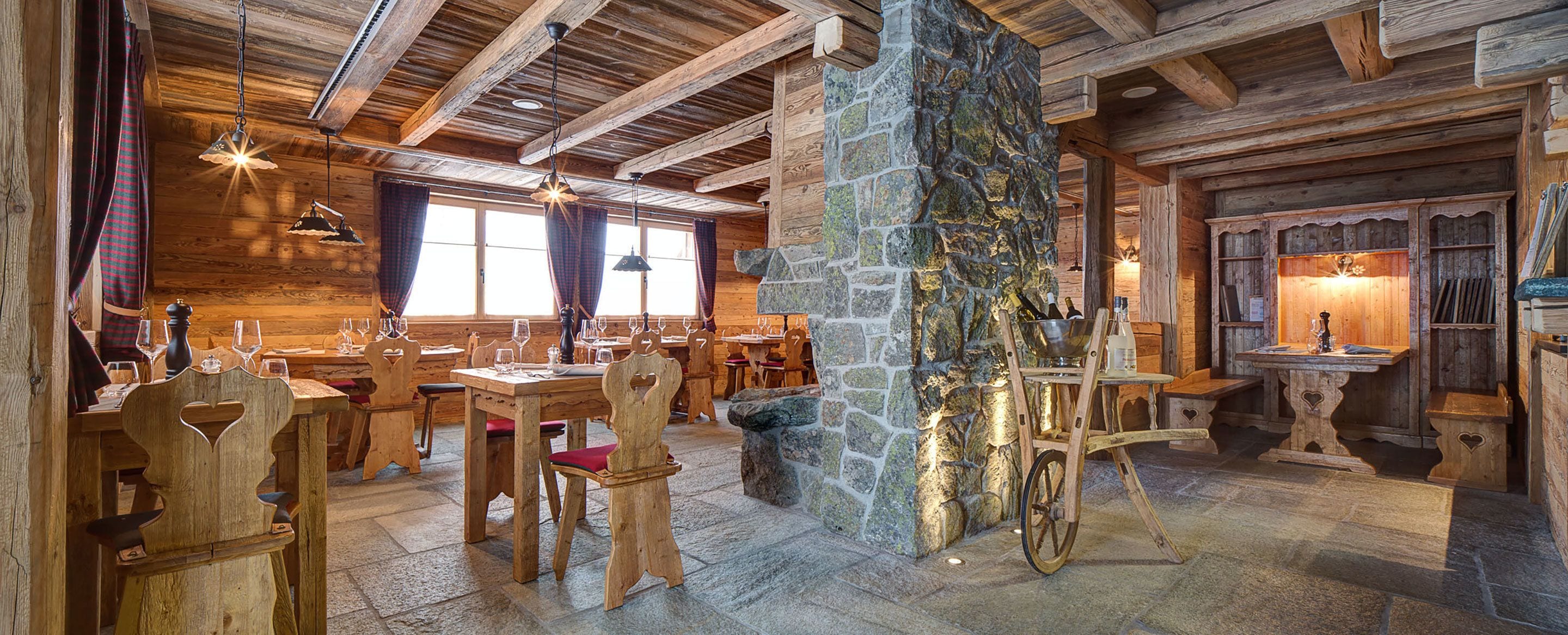 Un interior rústico de madera con paredes de piedra, mesas y sillas también de madera.