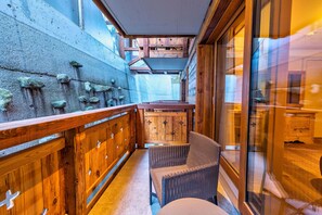 A narrow corridor with wooden walls, a wicker chair, and a wooden table. - Hôtel Nendaz 4 Vallées & Spa (Nendaz)