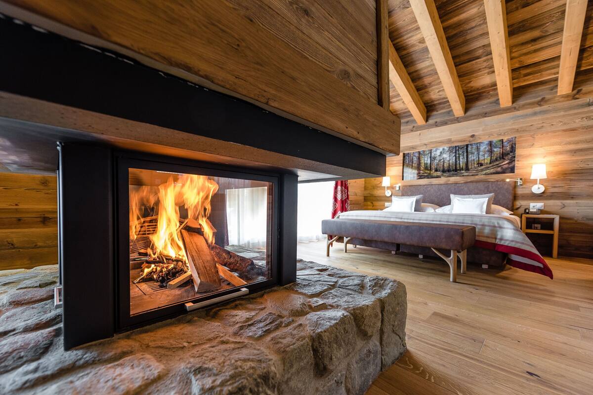 Una habitación acogedora con chimenea de piedra, una cama con cabecero y un cuadro en la pared.