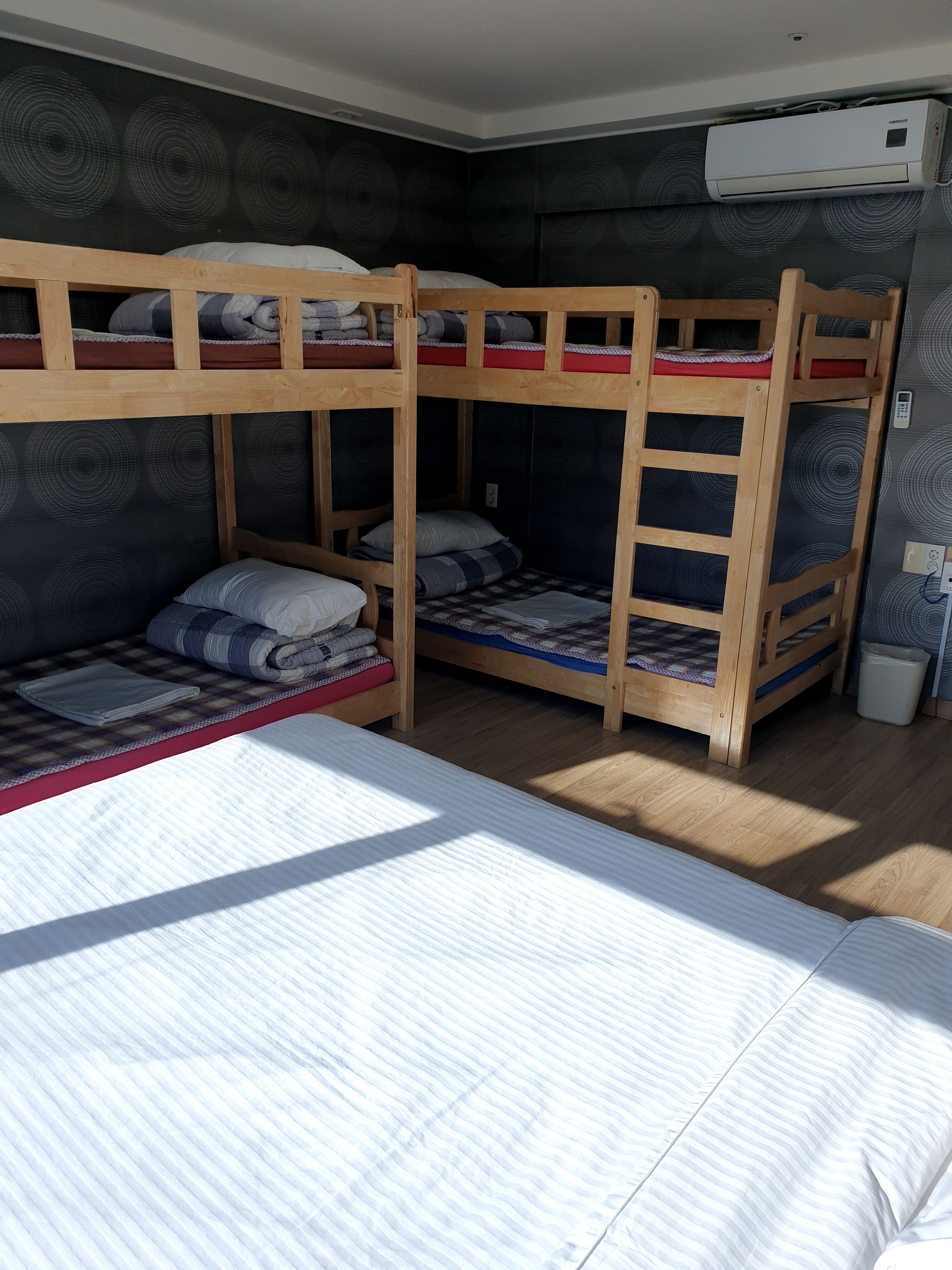 Dormitorio con literas, ventana, aire acondicionado instalado en la pared y un cesto de basura.