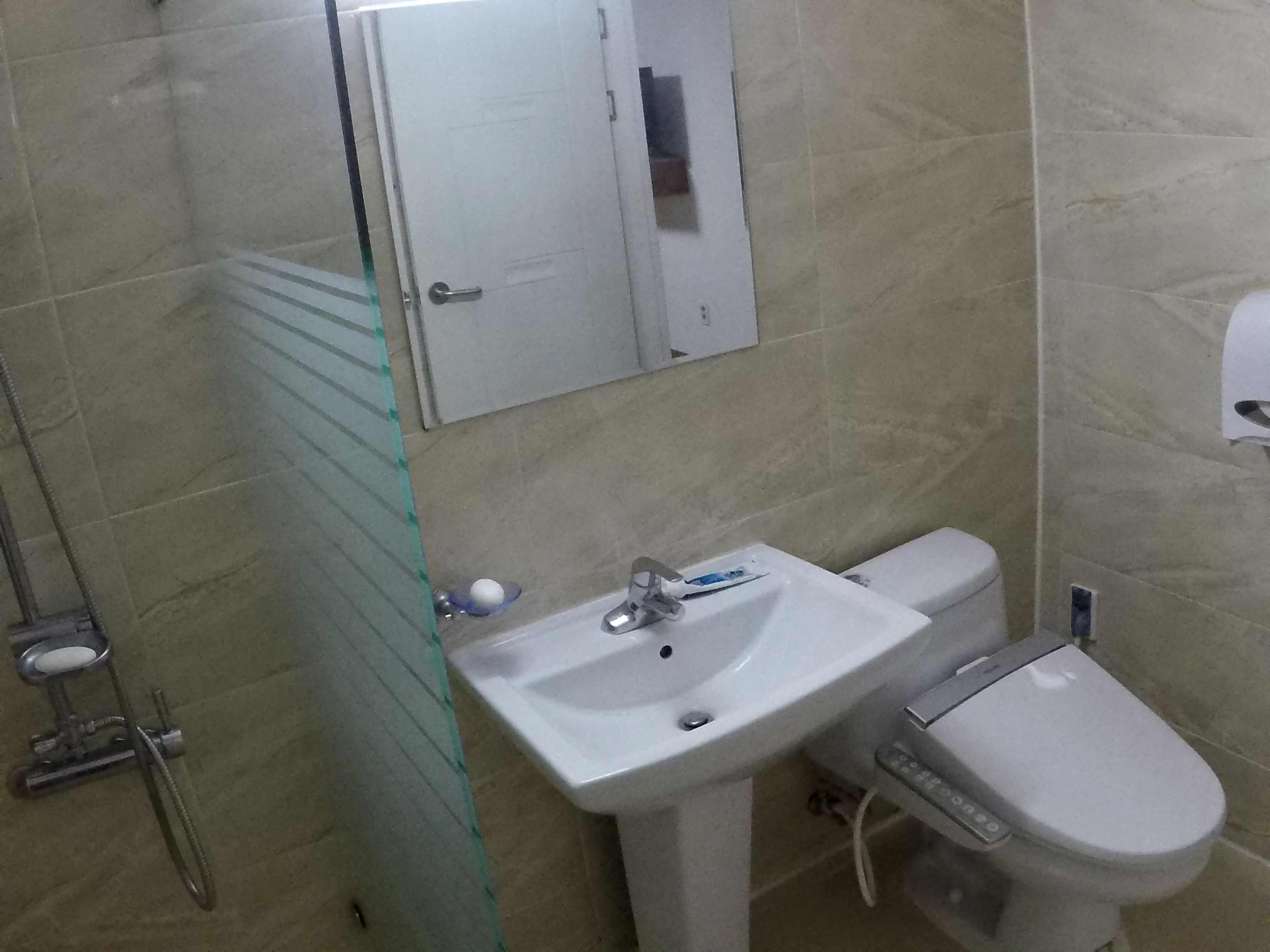 A bathroom with a glass shower enclosure, a white sink, and a toilet.