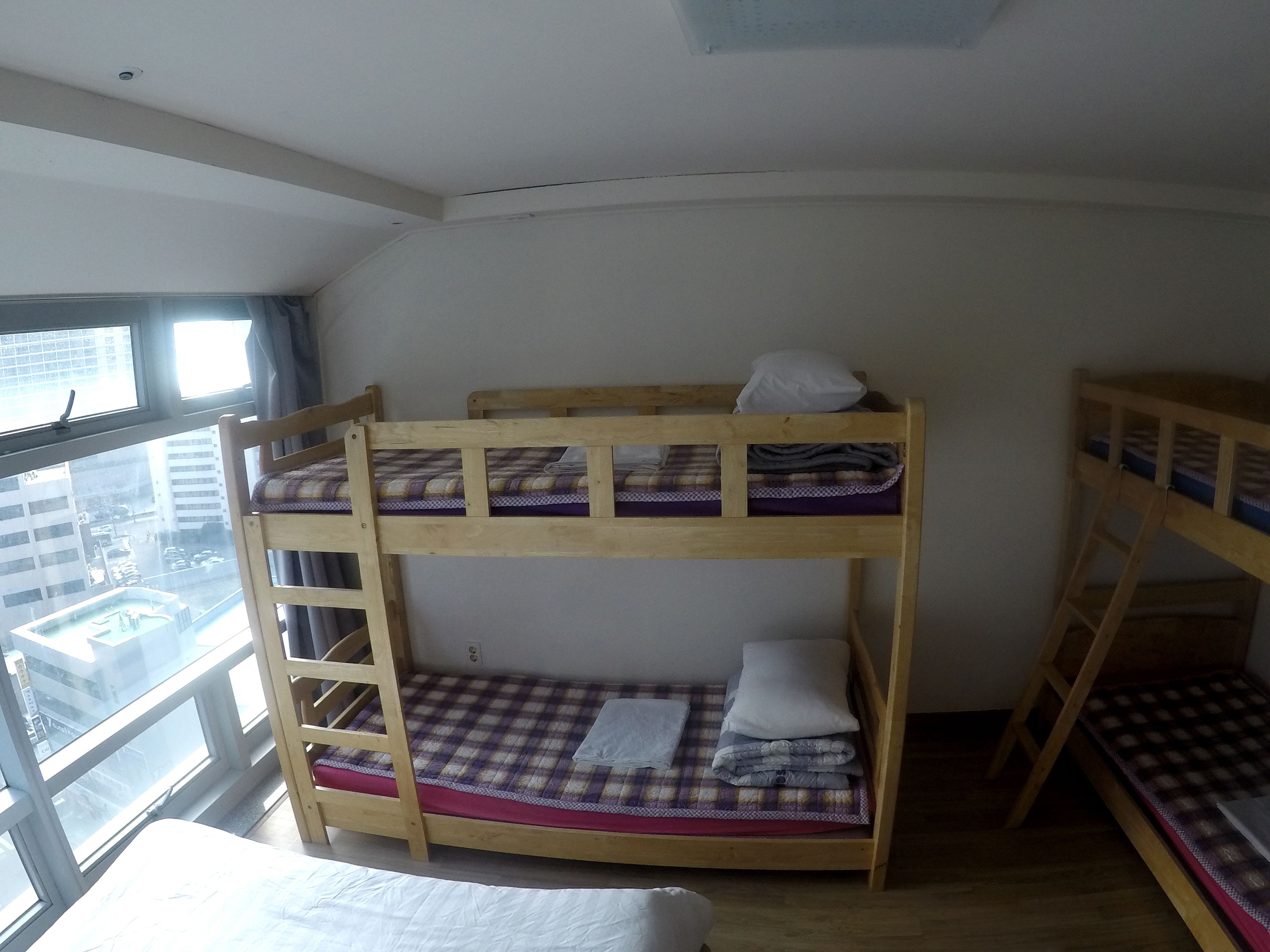 A bunk bed room with a window view of a cityscape.