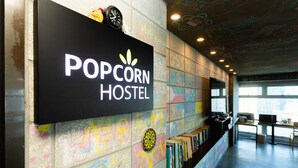Een muur met een bord waarop 'POPCORN HOSTEL' staat en een dartbord eronder.
