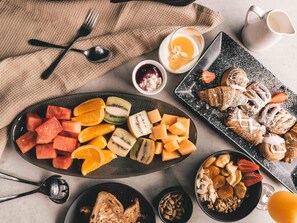 A breakfast spread with various fruits, pastries, and a jug of juice.
