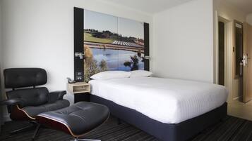 Een hotelkamer met een bed, een stoel, een nachtkastje en een tv aan de muur.