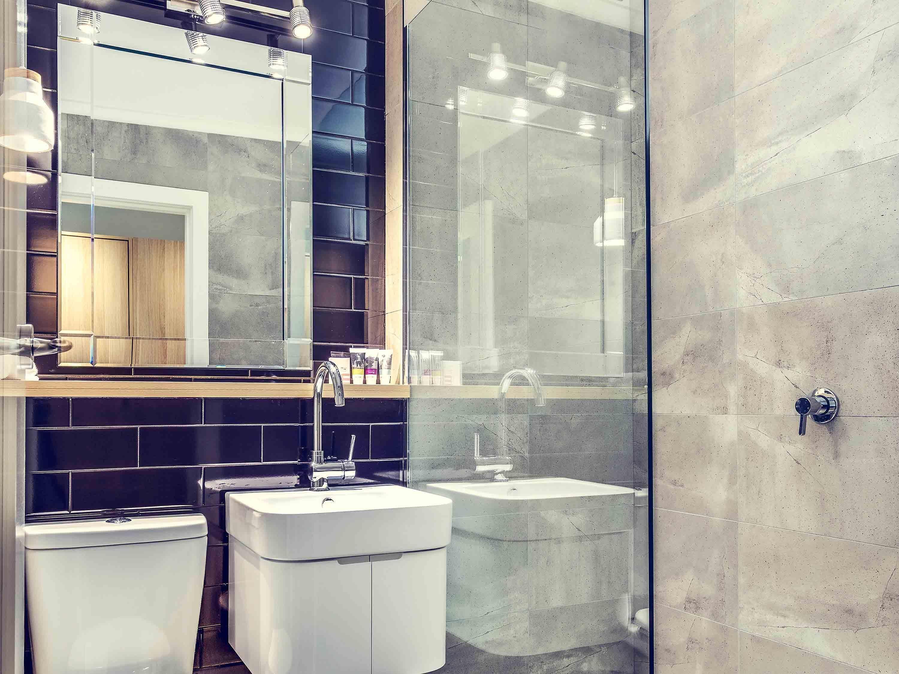 A modern bathroom with a glass shower enclosure, a white sink, and a toilet.