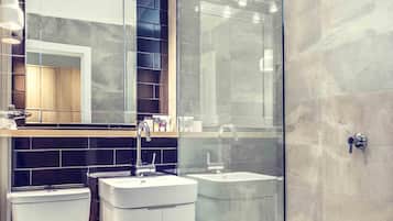 A modern bathroom with a glass shower enclosure, a white sink, and a toilet.