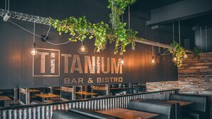Interior de restaurante con diseño moderno, que incluye una barra, cabinas y una pared rústica.