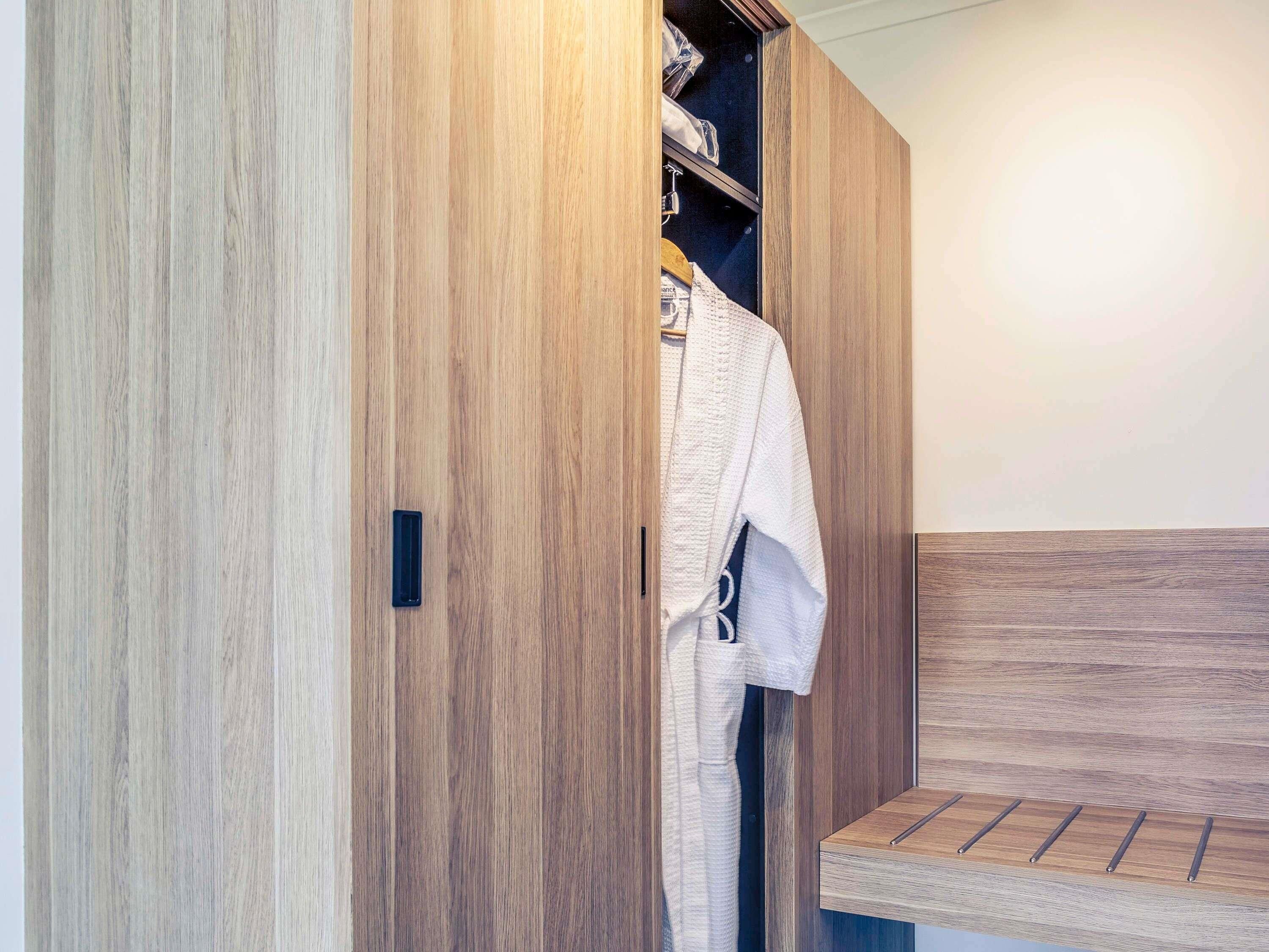 A wooden wardrobe with a hanging rack, a bench, and a small shelf.
