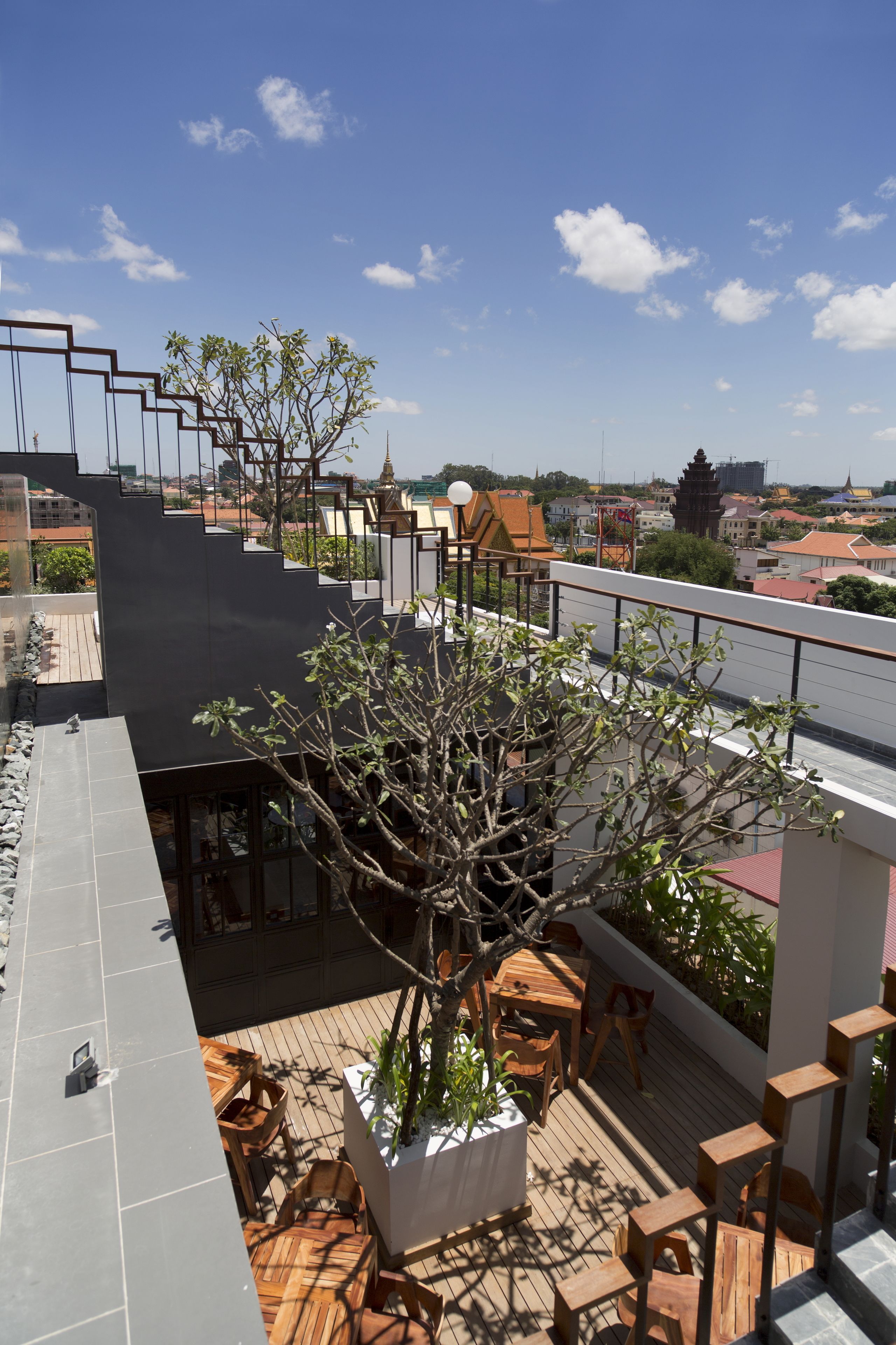 Une terrasse sur le toit, aménagée avec des meubles en bois, des plantes en pot et un escalier.