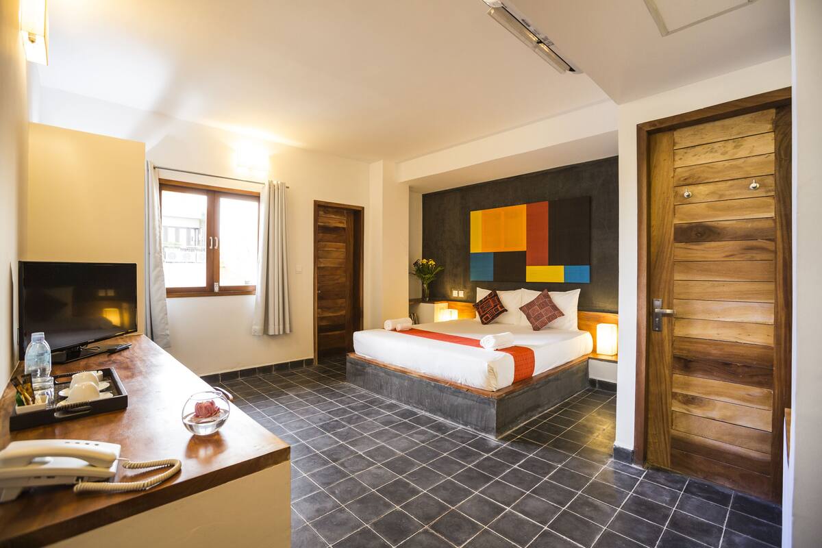 Ein Hotelzimmer mit Bett, Nachttisch, Fernseher und Blick nach draußen.