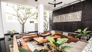 Un interior moderno con un conjunto de sofá de madera, un ventilador de techo y un gran elemento decorativo en la pared.