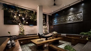 Un interior moderno con un rincón de asientos con banco de madera, un elemento decorativo en la pared e iluminación ambiental.
