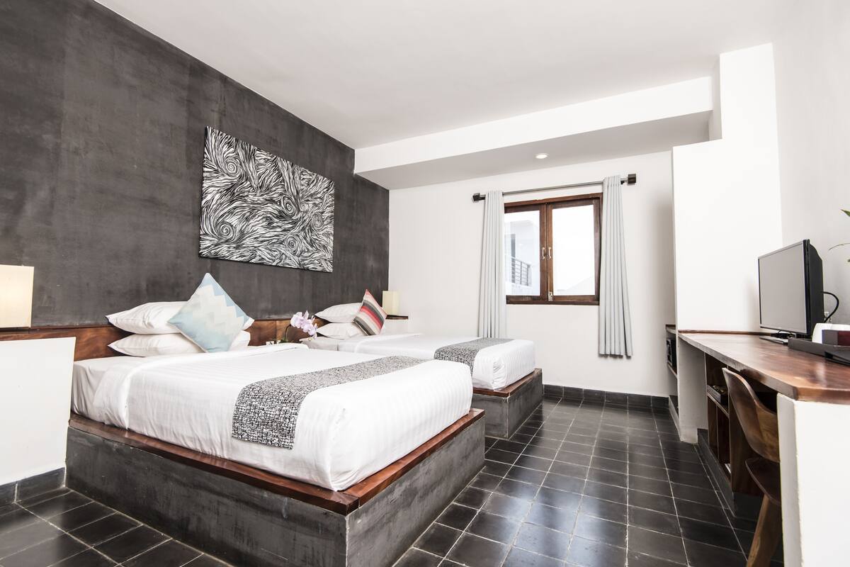 Ein modernes Hotelzimmer mit einem großen Bett, einem Schreibtisch und einem großen, abstrakten Gemälde an der Wand.
