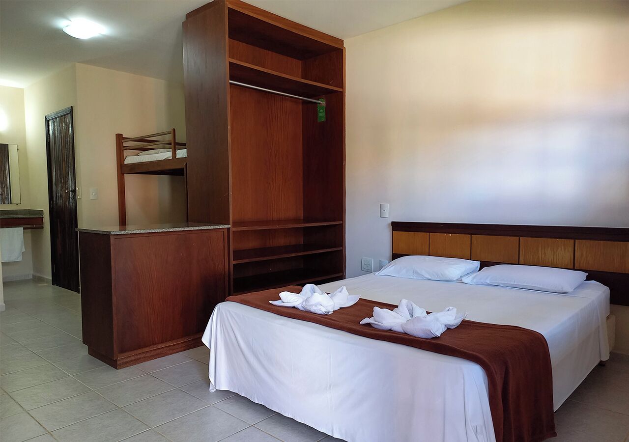 Een hotelkamer met twee bedden, een houten garderobe en een klein bureau.