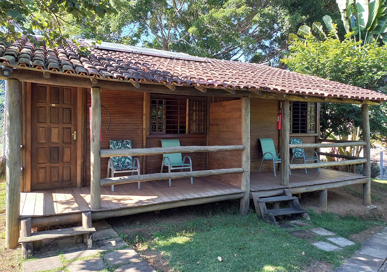 Een houten huis met een pannendak, een veranda met stoelen en een houten deur.