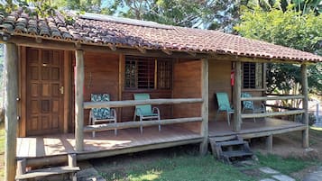 Een houten huis met een pannendak, een veranda met stoelen en een houten deur.