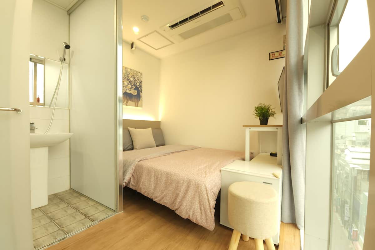 Een slaapkamer met een bed, nachtkastje en een klein krukje.