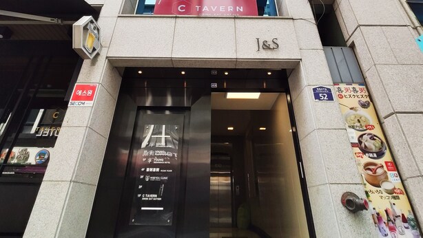 A building with multiple signs indicating a Young Residence Hotel, a Tavern, and a clinic. - OYO Hostel Myeongdong 2 (Seoul)