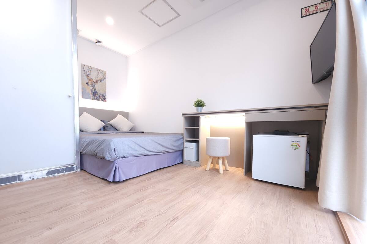 Een compacte slaapkamer met een bed, nachtkastje en een kleine witte koelkast.