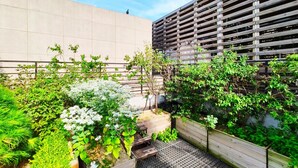 A rooftop garden with various plants and a wooden bench. - OYO Hostel Myeongdong 2 (Seoul)
