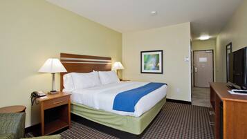 A hotel room with a bed, bedside lamps, a desk with a television, and a chair.