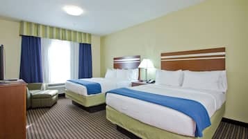 Habitación de hotel con dos camas, un escritorio, una silla y una ventana con cortinas.
