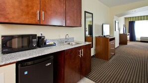 Una cocina de hotel con microondas, cafetera, fregadero y refrigerador.