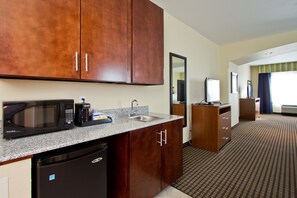 Una cocina de hotel con microondas, cafetera, fregadero y refrigerador.