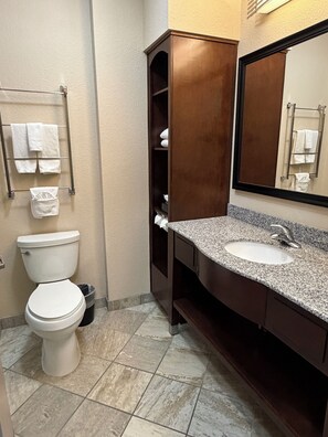 Un baño con inodoro, lavabo, espejo y perchero para toallas.
