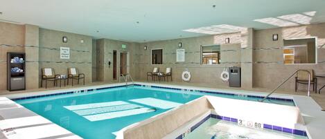 An indoor swimming pool with multiple lanes, a lifeguard chair, and a pool rules sign.