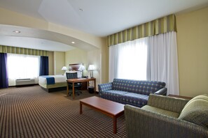 Una habitación de hotel con cama, sofá, mesita y escritorio con lámpara.