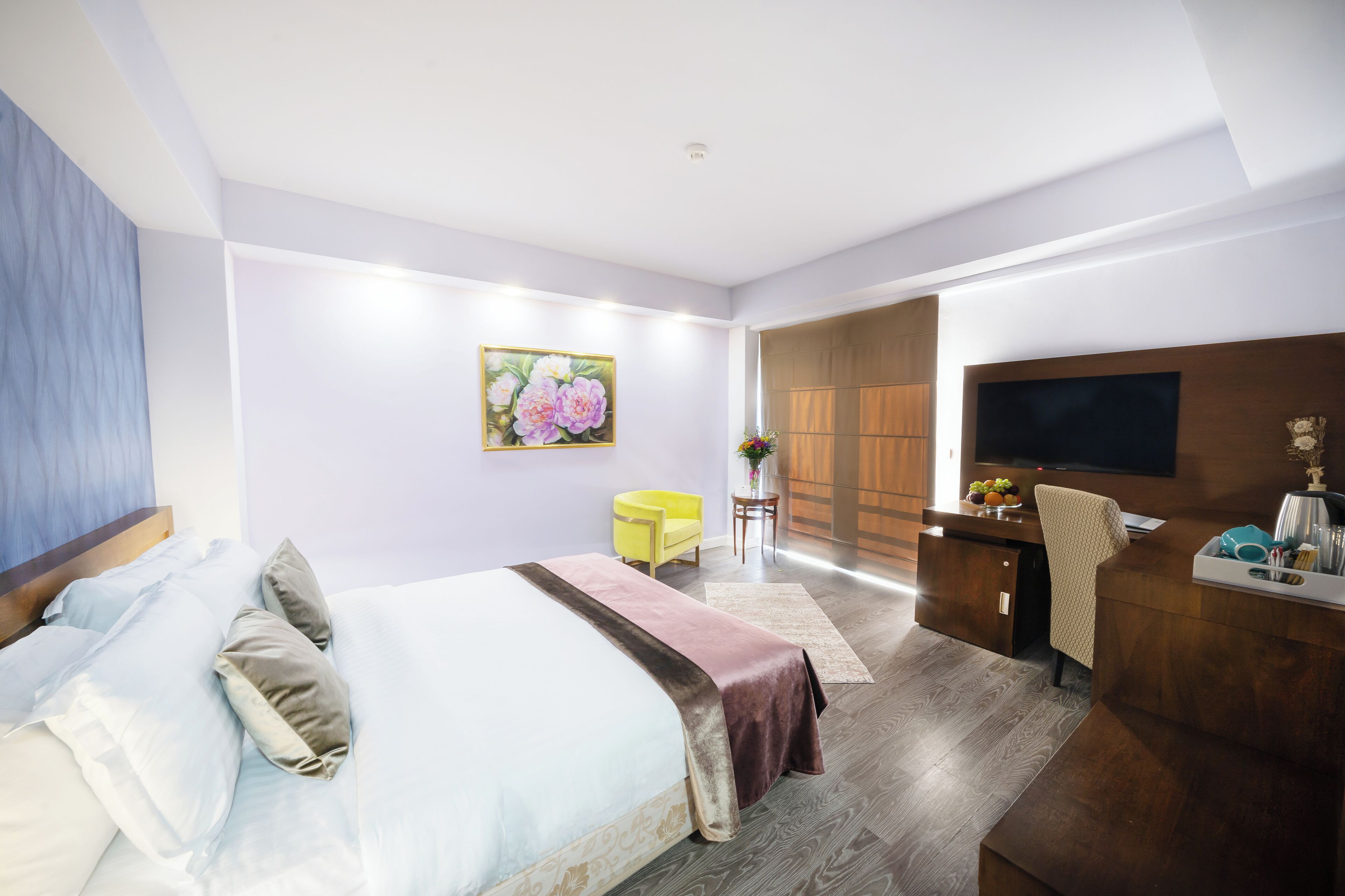 A modern hotel room with a bed, a desk, a TV, and a chair.