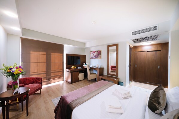 A hotel room with a bed, a desk with a chair, a TV, a wardrobe, and a bathroom. - Phoenicia Comfort Hotel (Bucharest)