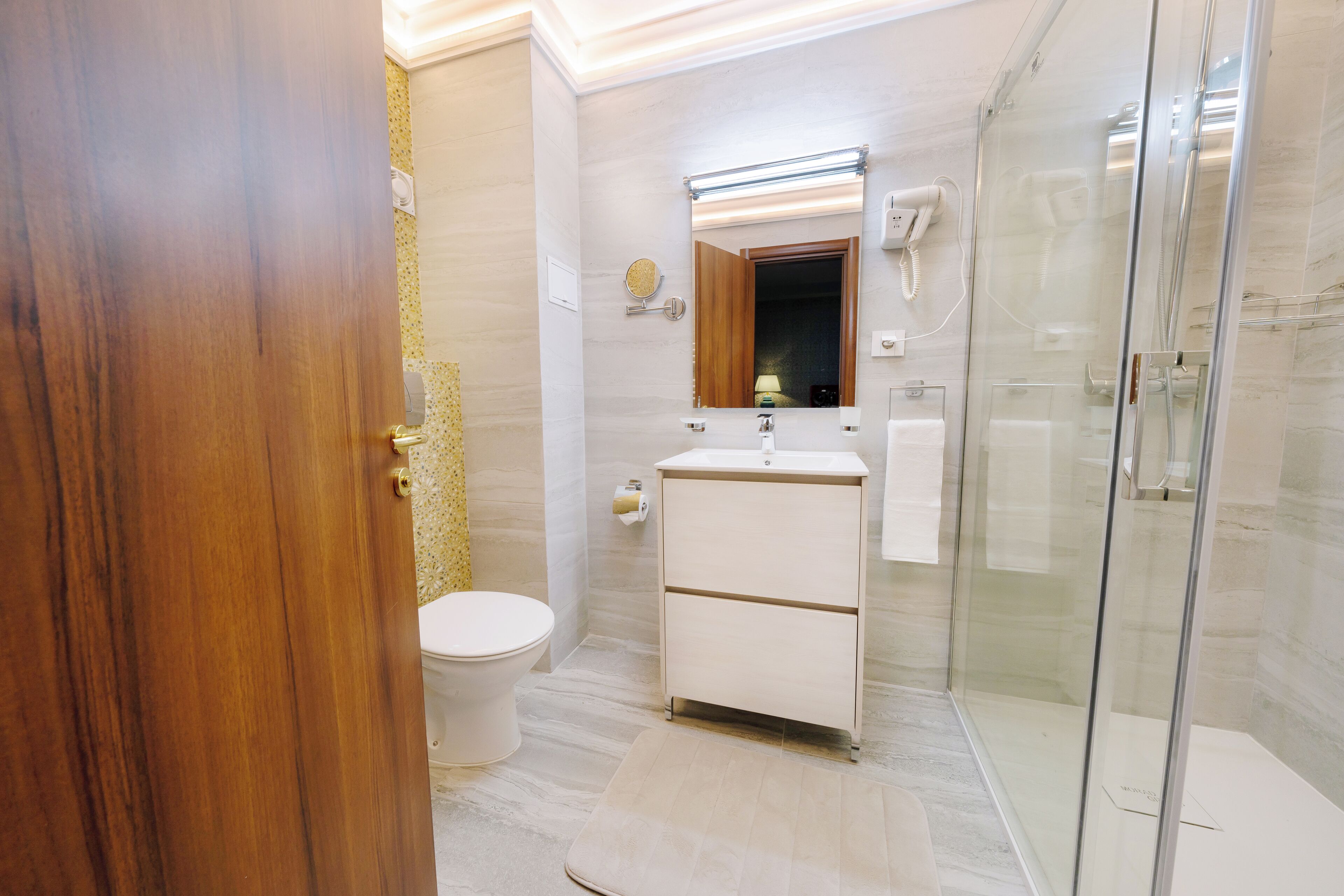 Een moderne badkamer met toilet, wastafel en douchecabine met glazen wanden.