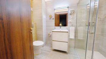 Een moderne badkamer met toilet, wastafel en douchecabine met glazen wanden.