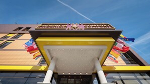 Het uiterlijk van het Renaissance Hotel, herkenbaar aan de opvallende geel-bruine gevel, een ruime entreekap en verschillende nationale vlaggen.