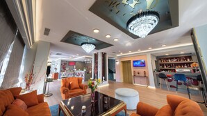 Een ruime lobby met een bar, zitgedeeltes en een kroonluchter.
