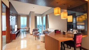 A modern hotel room with a wooden reception desk, a seating area with a sofa and chairs, a large window with a city view, and pendant lighting. - Swiss Belinn SKA Pekanbaru (Pekanbaru)