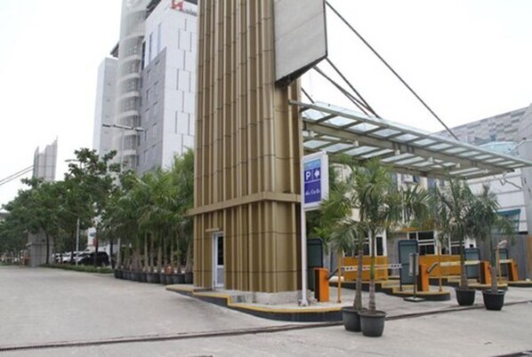 A modern building with a parking sign, a covered entrance, and a row of palm trees.