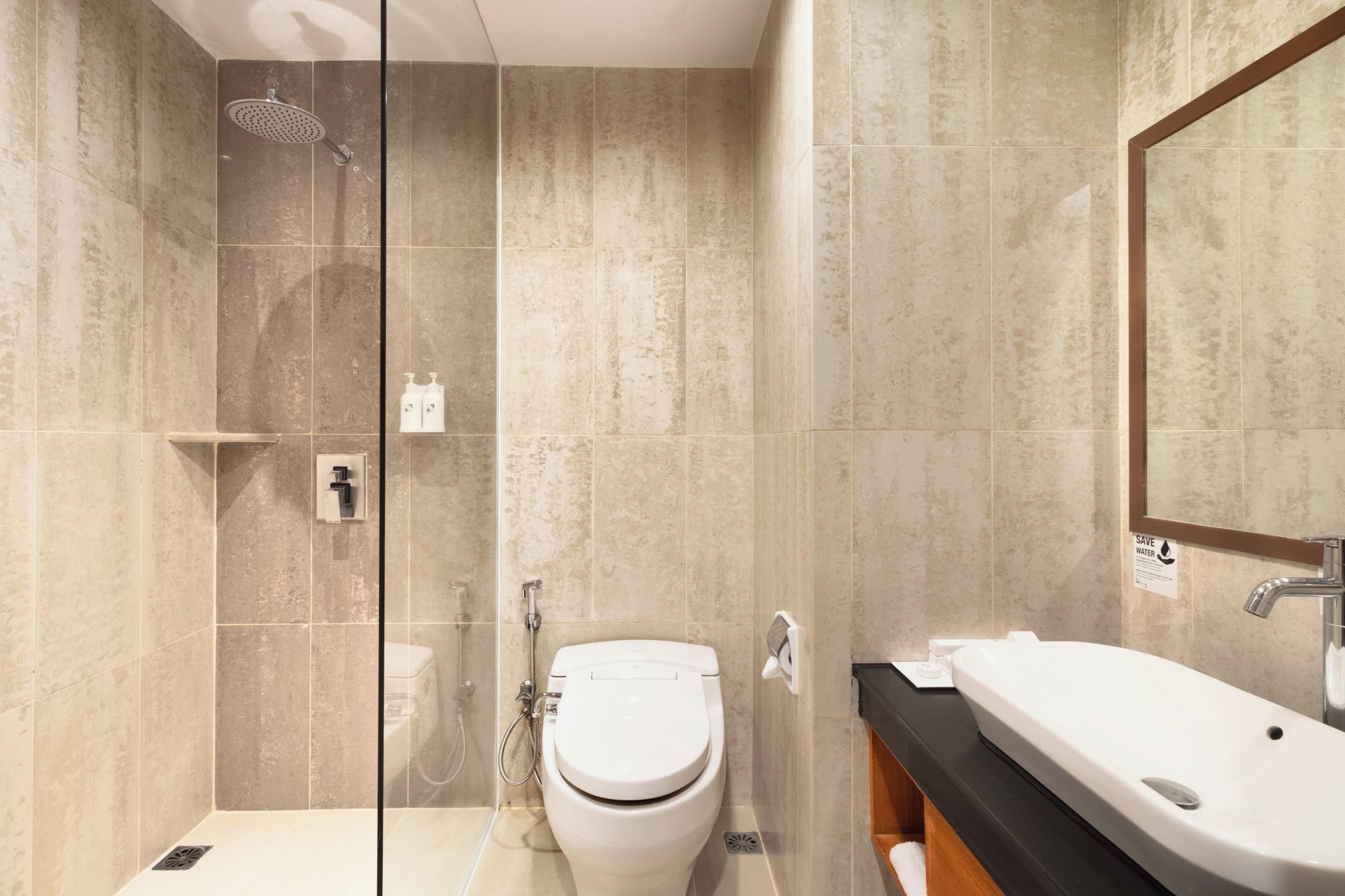 A modern bathroom with a glass shower enclosure, a toilet, and a sink with a mirror above it.