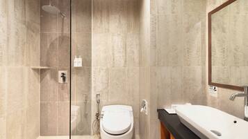 A modern bathroom with a glass shower enclosure, a toilet, and a sink with a mirror above it.