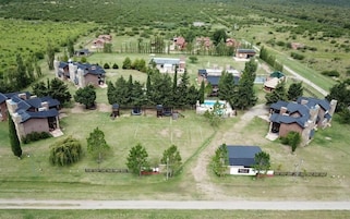 Vista aérea de una zona residencial con varias casas, un parque infantil y una piscina.