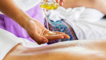 A person pouring oil on another person's back.