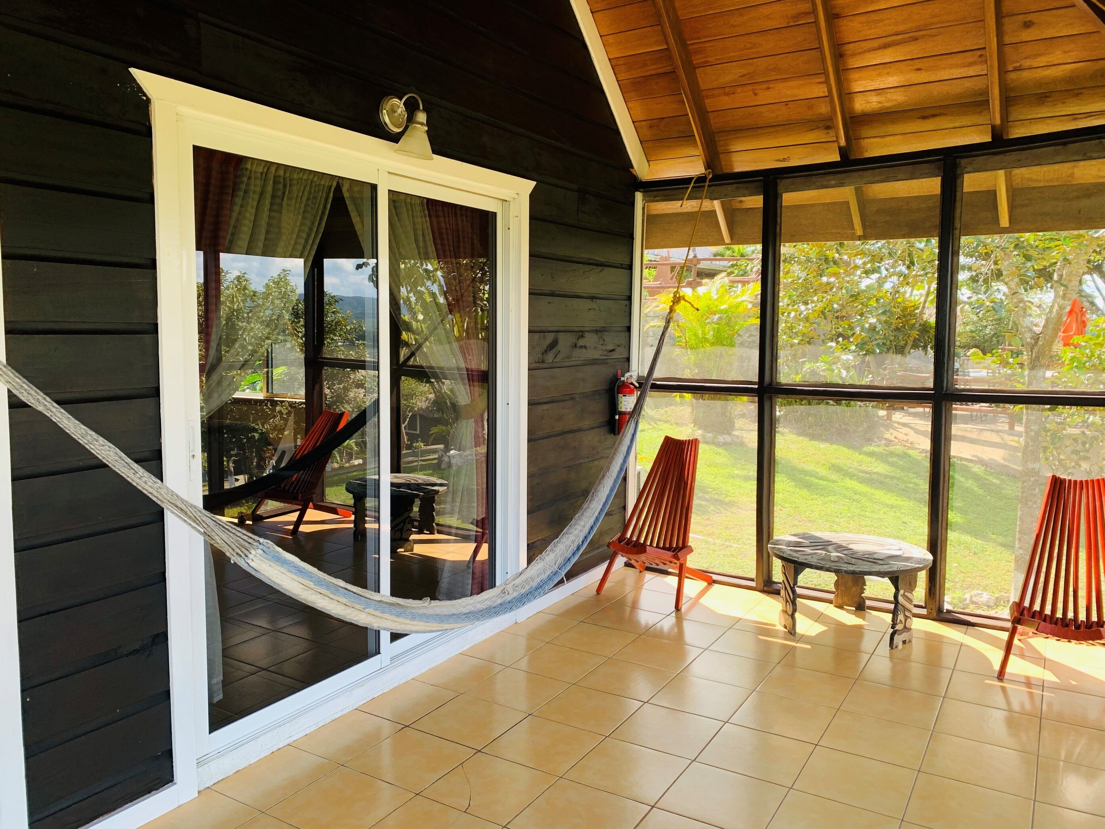 A room with a large window, a hammock, and a fire extinguisher.
