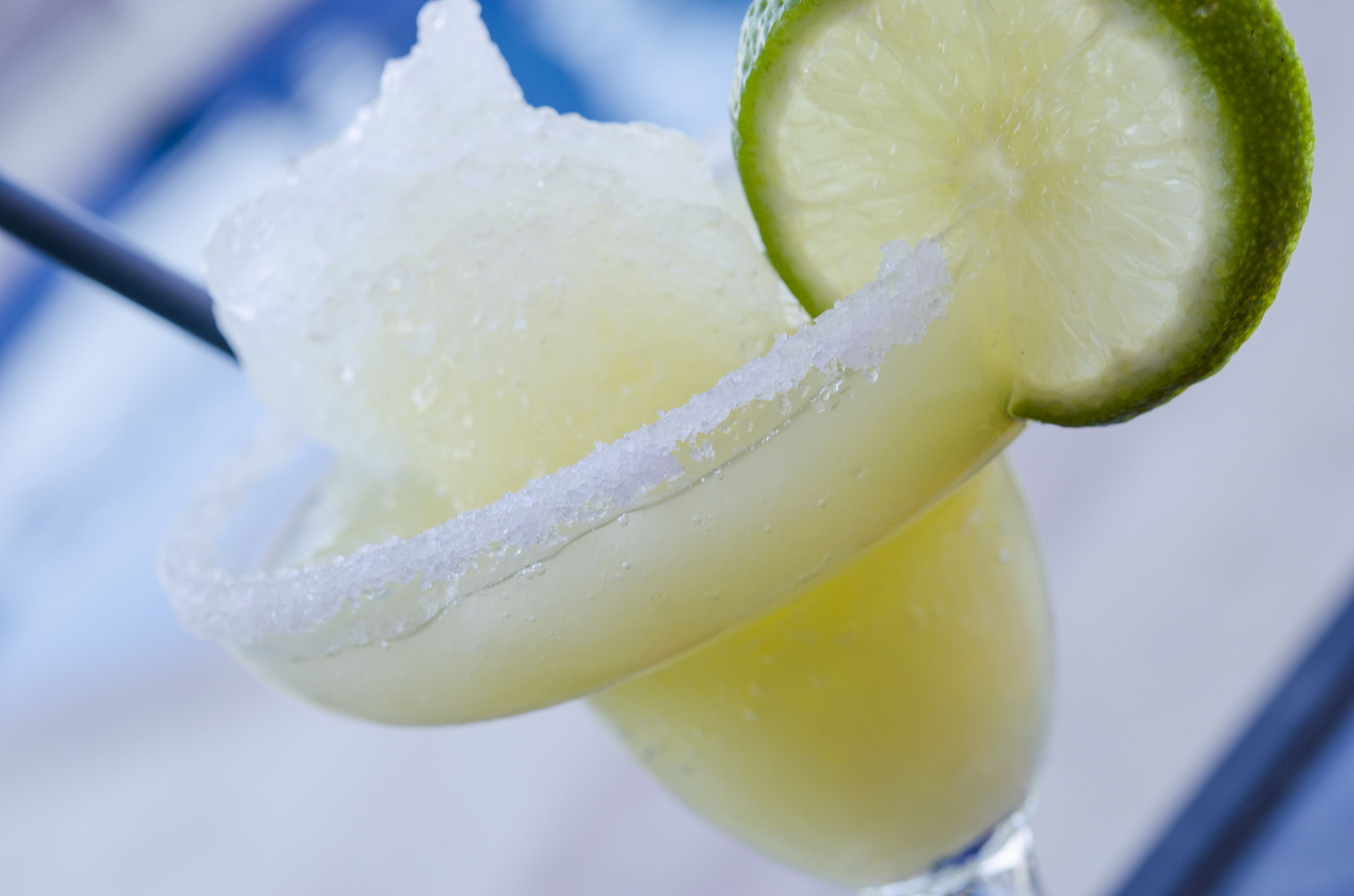 A close-up of a lime wedge on a glass rim with salt.