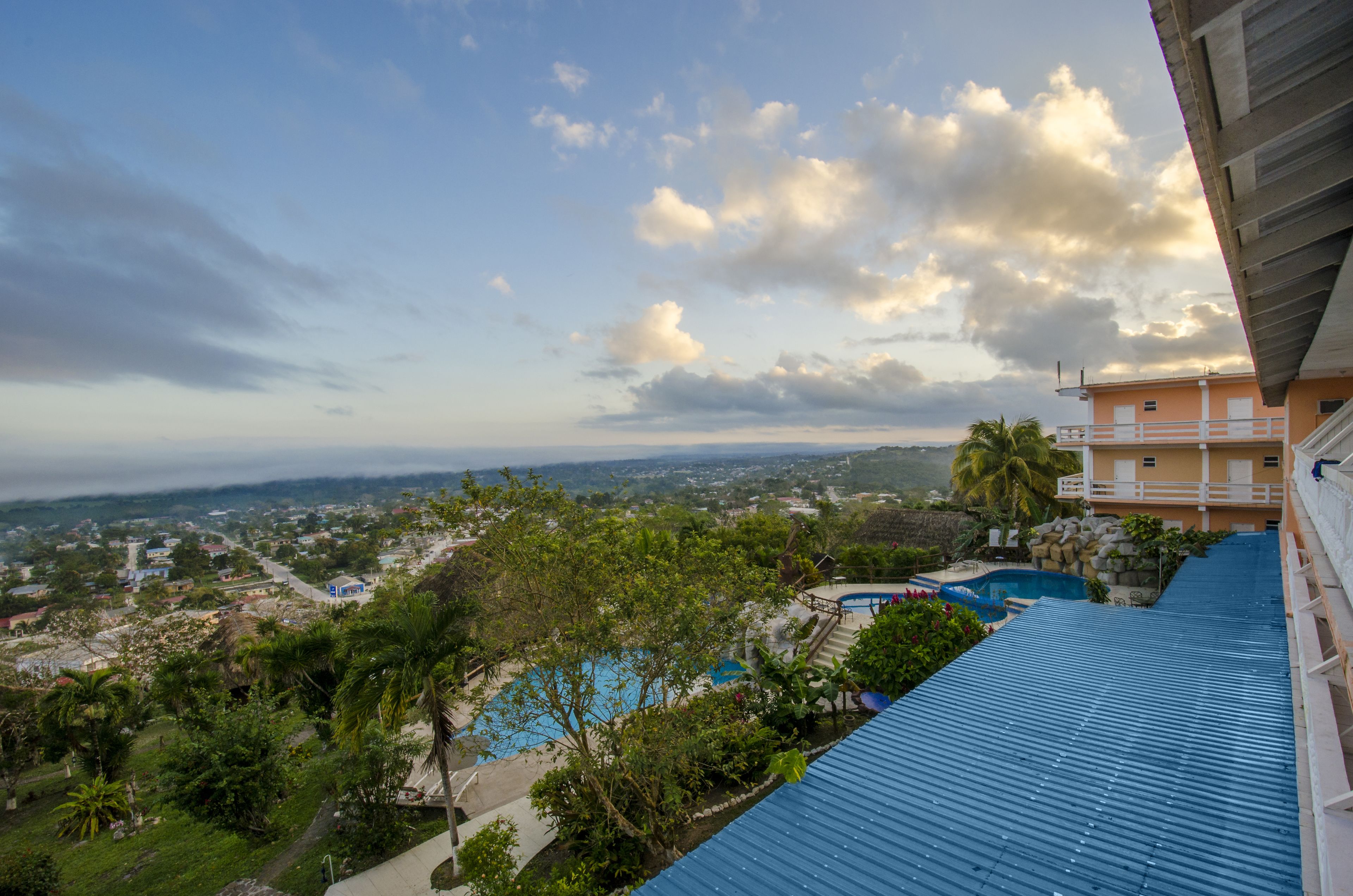 A residential area with a swimming pool, lush greenery, and a view of the cityscape.