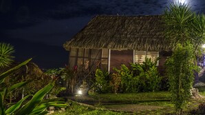 Ein reetgedecktes Haus mit Holzfassade, umgeben von üppigem Grün und einem kleinen Garten.